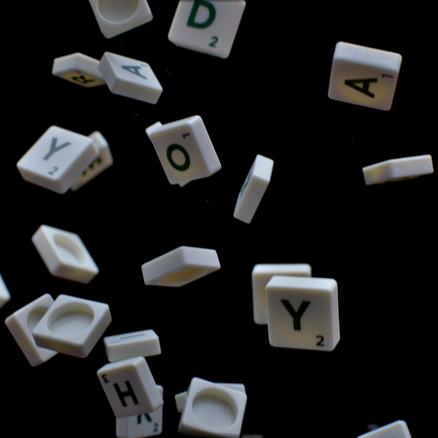White letter tiles drop through the air on a black background